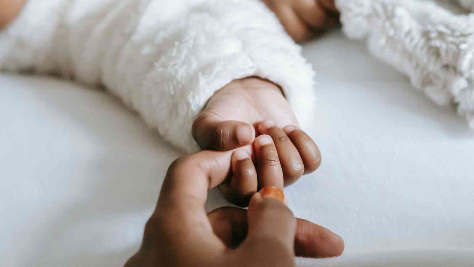 Caregiver reaching out to touch a babies hand